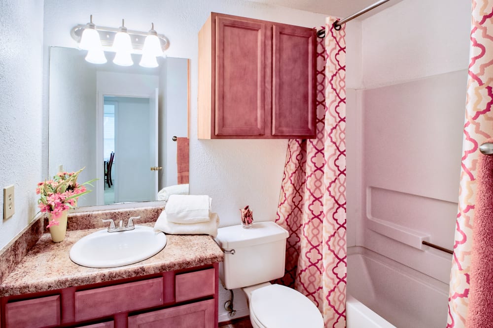 Cherry-colored cabinets in an apartment bathroom at Royal Pointe in Virginia Beach, Virginia