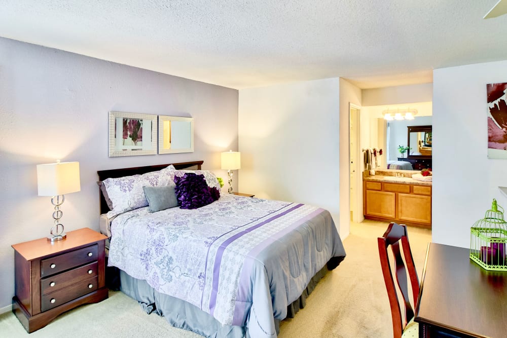 A furnished main bedroom with a king-sized bed and attached bathroom at Royal Pointe in Virginia Beach, Virginia