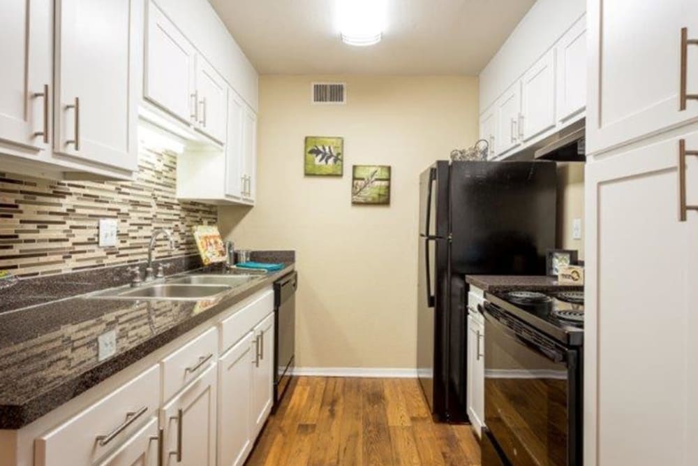 Hallway apartment kitchen with black appliances at Acasă Prosper Fairways in Columbia, South Carolina