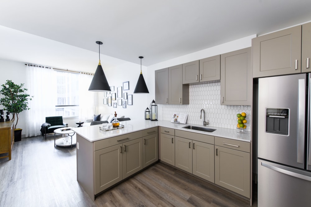 Model apartment kitchen with hardwood floors and stainless-steel fridge at Clearwater at The Heights in Houston, Texas