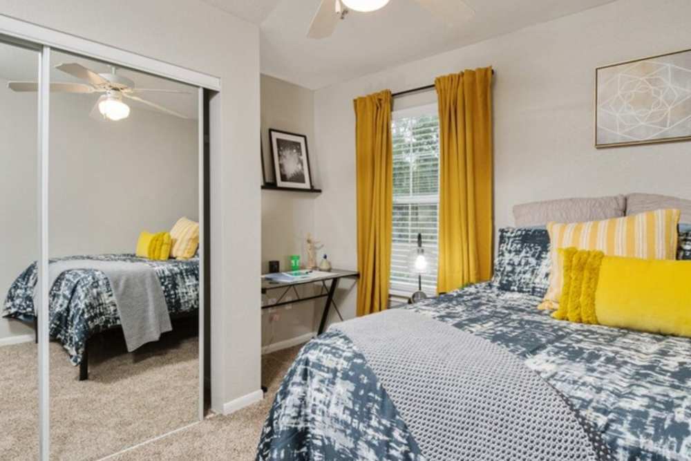 Apartment bedroom with yellow drapes and a mirror closet at Acasă Bainbridge in Tallahassee, Florida