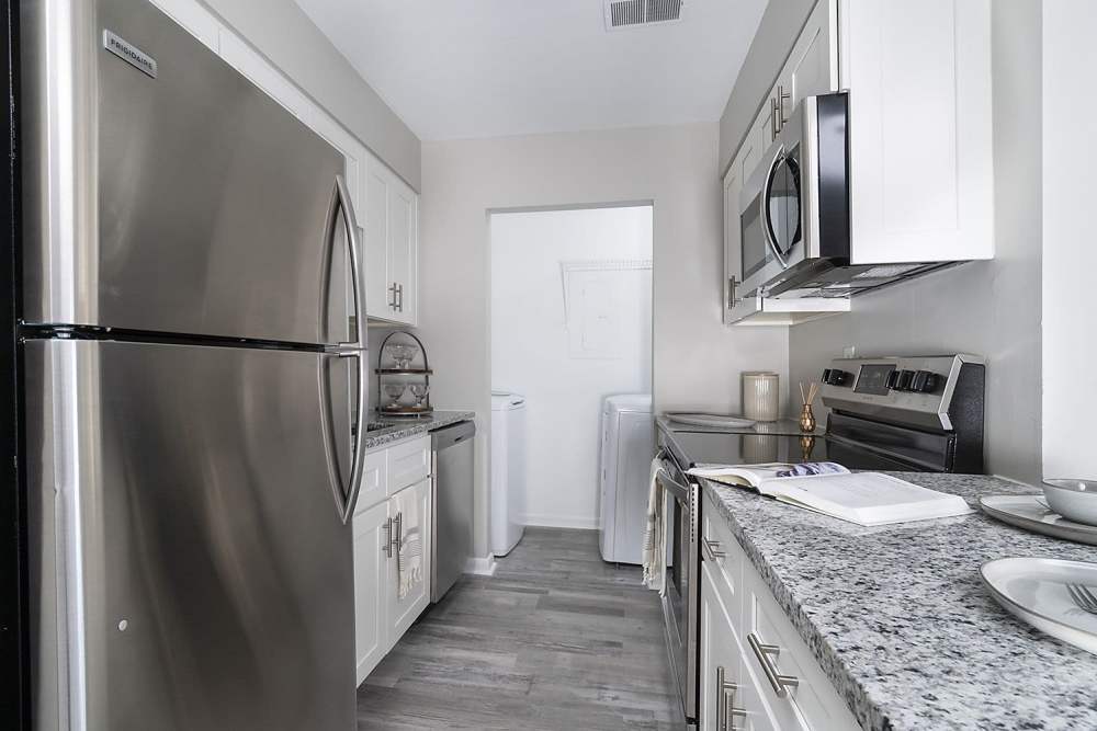 Hallway apartment kitchen with stainless steel finishes at Acasă Orchard Park Apartments in Greenville, South Carolina