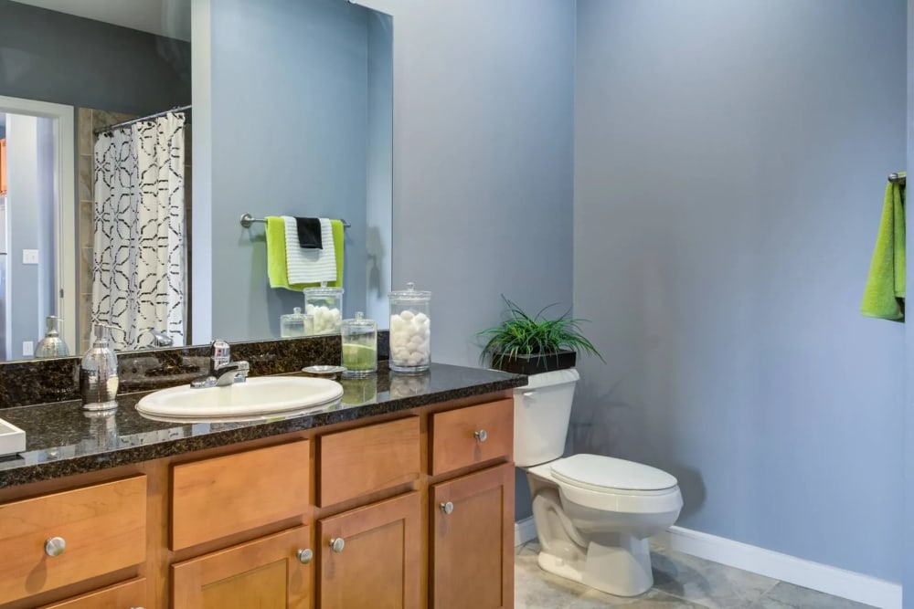Apartment bathroom with large mirror and granite counter at The Landing at St. Louis in Saint Louis, Missouri
