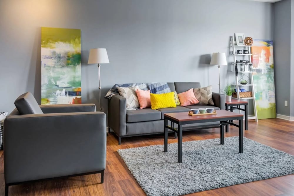 Apartment living room with area rug, upholstered sofa, and chair at The Landing at St. Louis in Saint Louis, Missouri