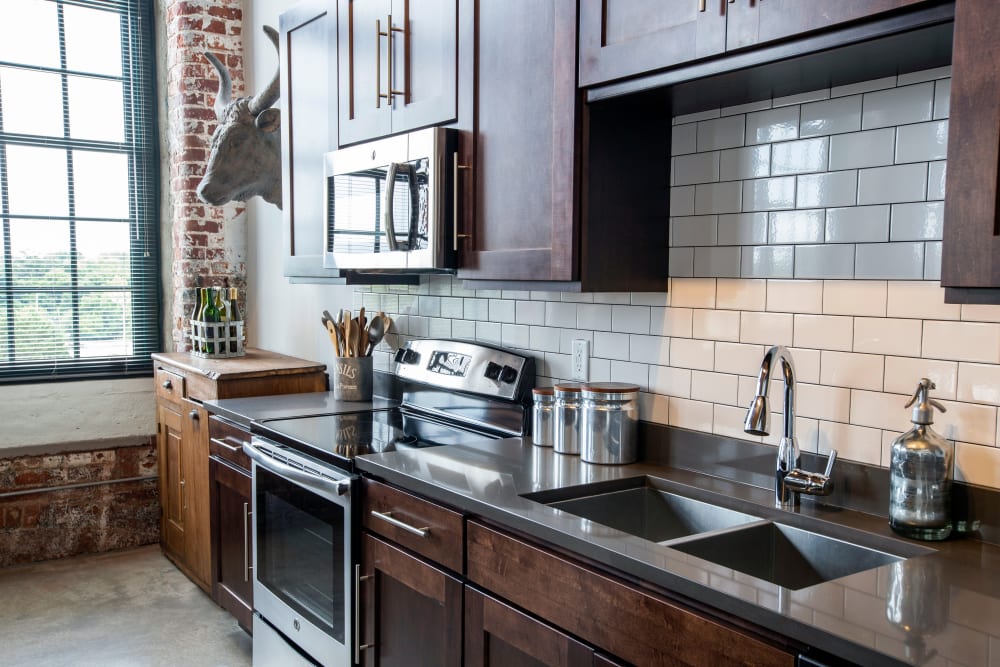 Modern kitchen with stainless-steel appliances and wood cabinetry at West Village Lofts at Brandon Mill in Greenville, South Carolina
