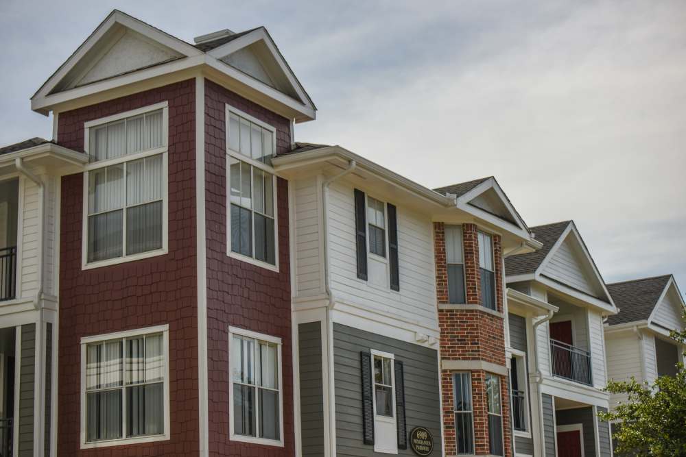 A row of apartment buildings with red and gray siding at Flatiron District at Austin Ranch, The Colony, Texas