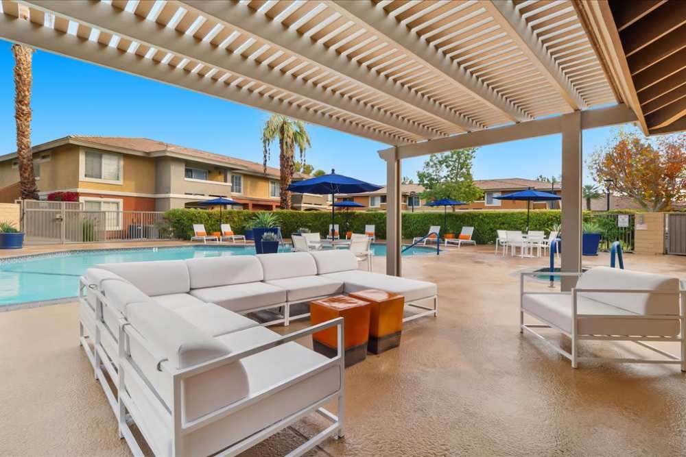 Shaded outdoor seating area next to pool at Mirabella Apartments in Bermuda Dunes, California