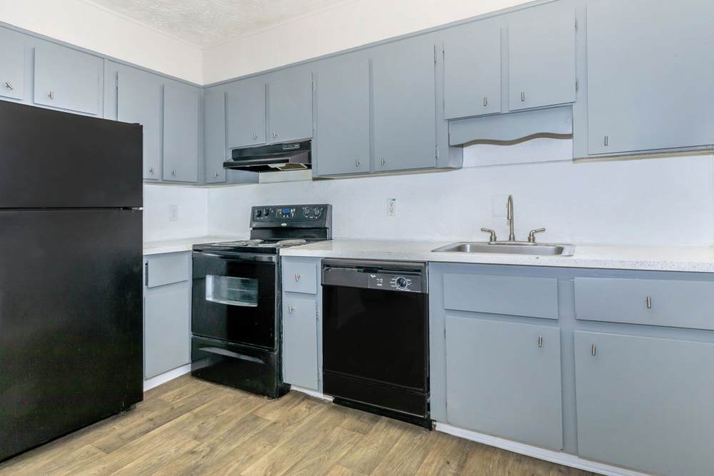 apartment kitchen with light blue cabinets and black appliances at The Carolina in Lawrenceville, Georgia
