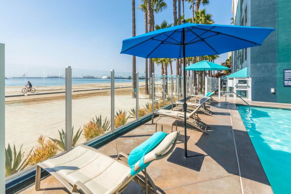 Community pool with sun loungers at 1900 Ocean Apartment Homes in Long Beach,California