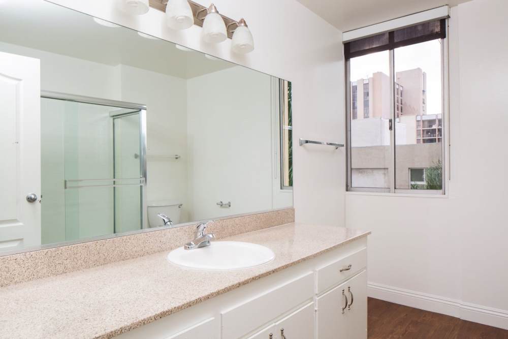 Bright bathroom with a large mirror at 1900 Ocean Apartment Homes in Long Beach,California
