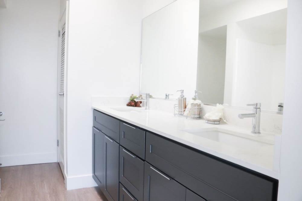 Bathroom with dark colored vanity unit and white countertop at 1900 Ocean Apartment Homes in Long Beach, California