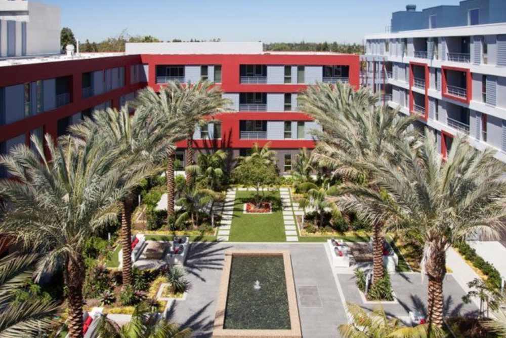 Aerial view of the apartment building with trees all around at The Marke Apartment Homes in Santa Ana, California