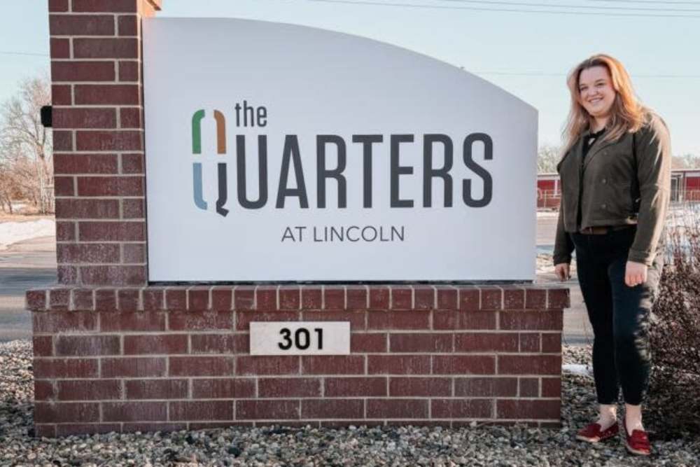 Team member standing by The Quarters at Lincoln sign at The Quarters at Lincoln in Lincoln, Nebraska