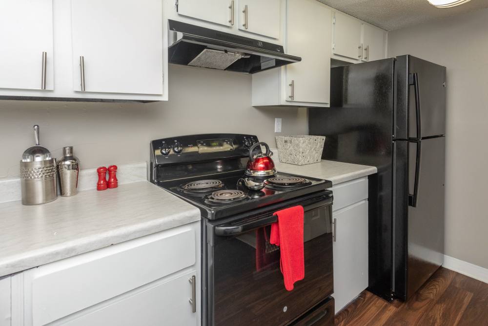 Apartment kitchen with white cabinets and black appliances at Acasă High Road in Tallahassee, Florida