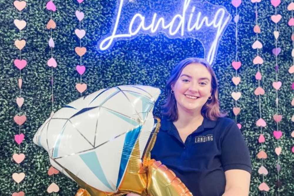 Staff member with Valentine's Day decorations and neon sign at The Landing at College Station in College Station, Texas