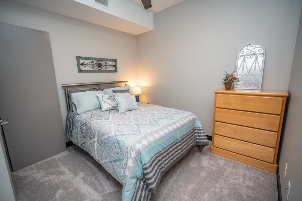 A bedroom with comfortable bed, dresser, and nightstand at Diamond Place I in Grand Rapids, Michigan