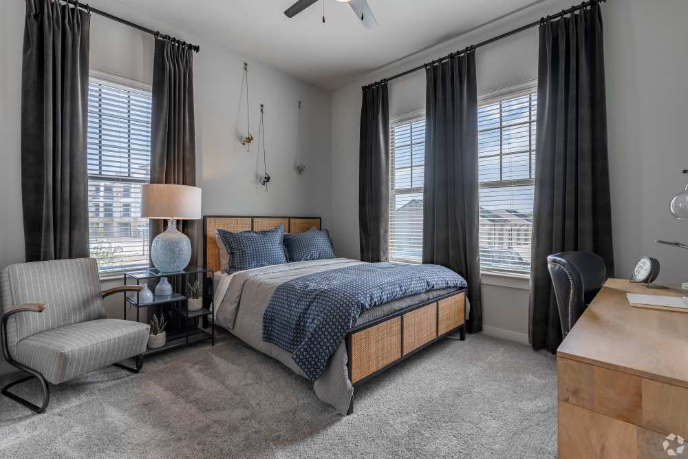 Bedroom with large windows and ceiling fan in a model home at The Trails at Summer Creek in Fort Worth, Texas