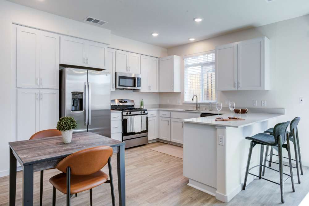 A modern kitchen with a dining area next to it at The Terraces at Stanford Ranch II in Rocklin, California