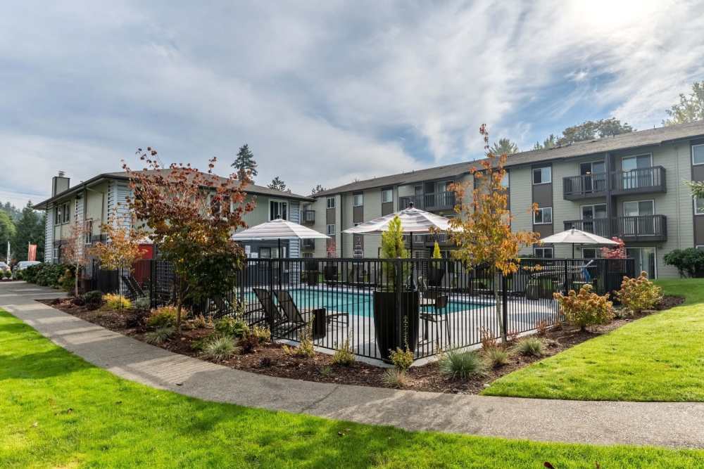 Property grounds with grass hills, swimming pool, and building exterior at Terra Apartment Homes in Federal Way, Washington