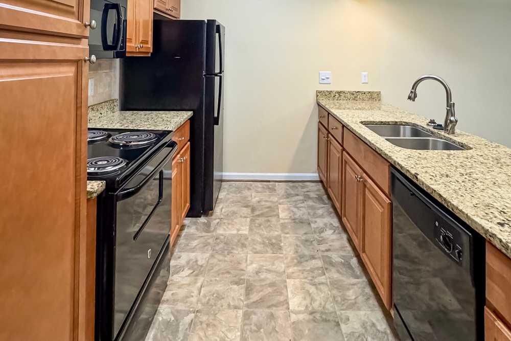 Modern kitchen with granite countertops and stainless steel appliances at The Village on Cherokee in Columbus, Georgia