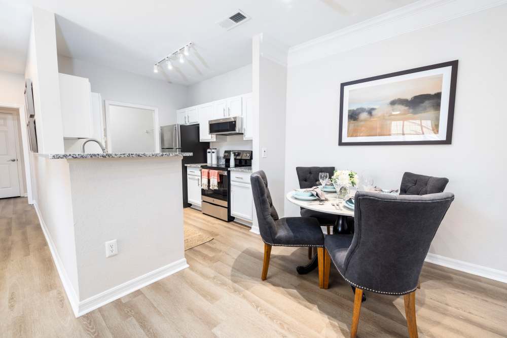 A dining table and chairs next to the kitchen in a model apartment at Arbors at Cahaba River in Birmingham, Alabama