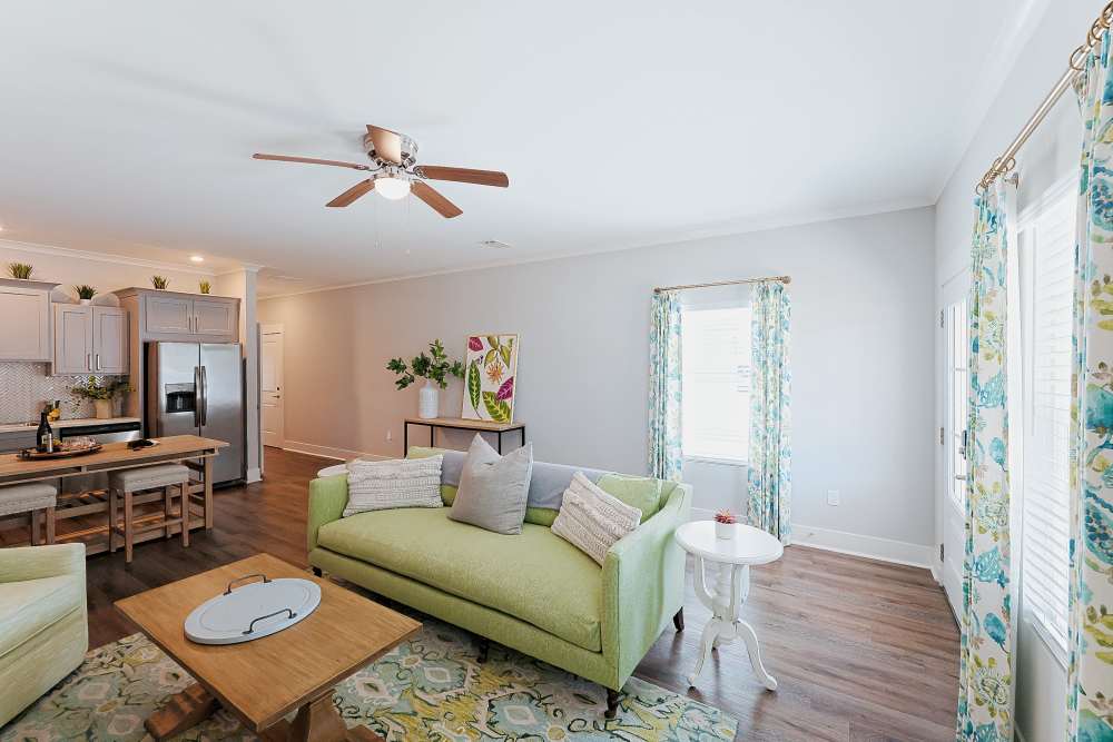 Living room with wood floors and a ceiling fan in a model home at Beverly Villas in Brunswick, Georgia