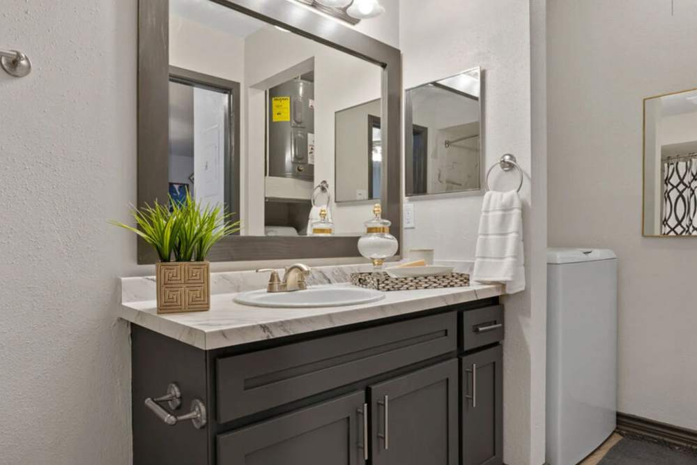 Vanity space with a granite countertop, and large mirror at Hill At Woodway in San Antonio, Texas