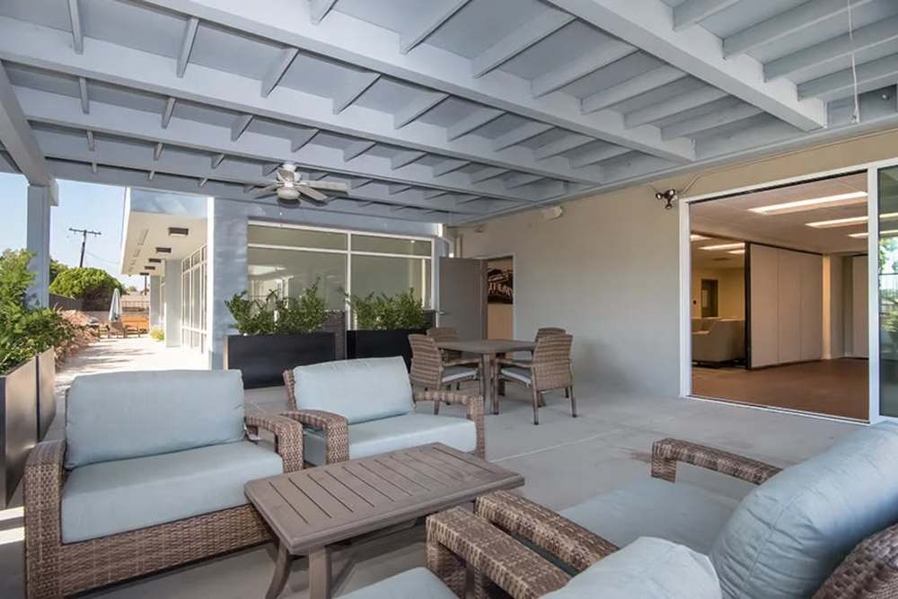 Outdoor community patio with comfortable seating at Bellflower Friendship Manor in Bellflower, California