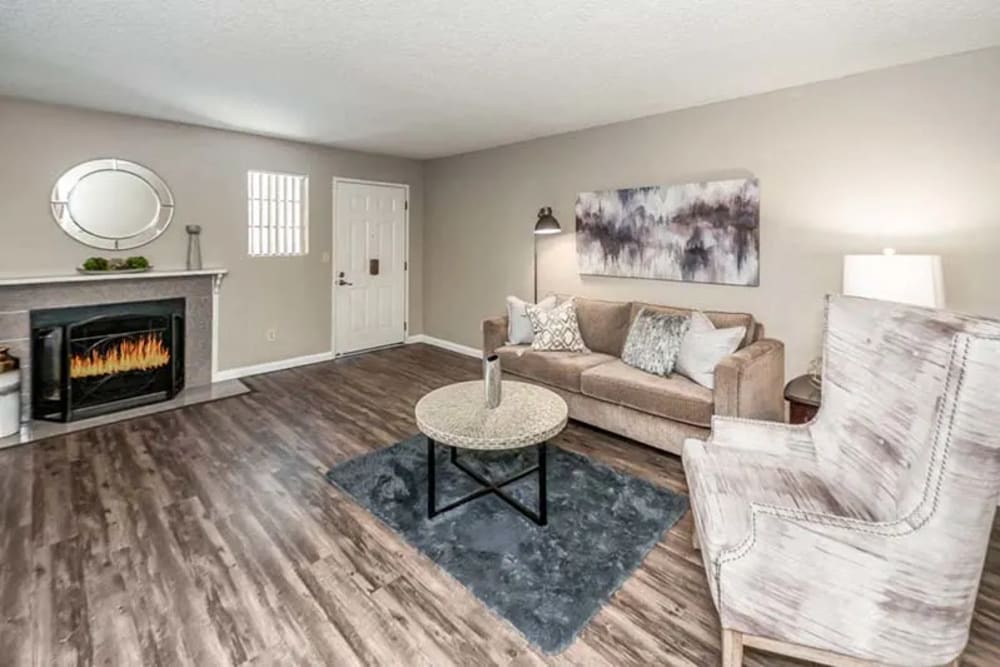 Spacious liviing room with wood-burning fireplace, wood-style flooring and sofa set matching the theme at Woodlake Close in Sacramento, California