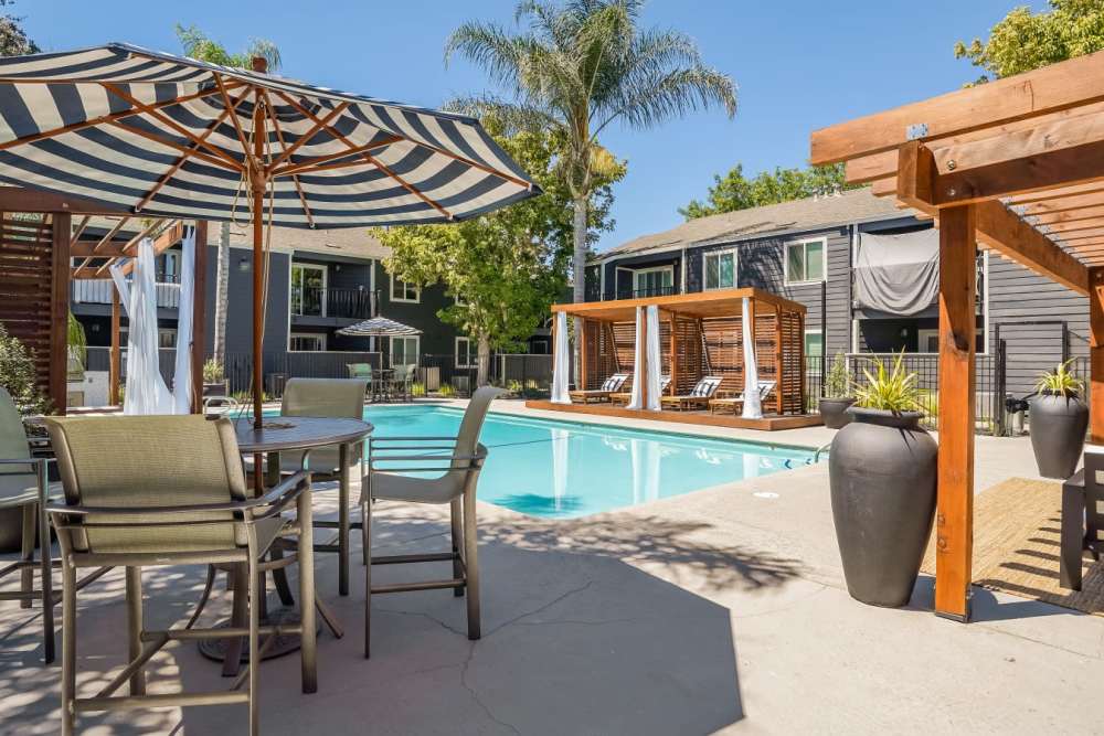Seating under a patio umbrella by the pool at Trails at 2112 in Modesto, California