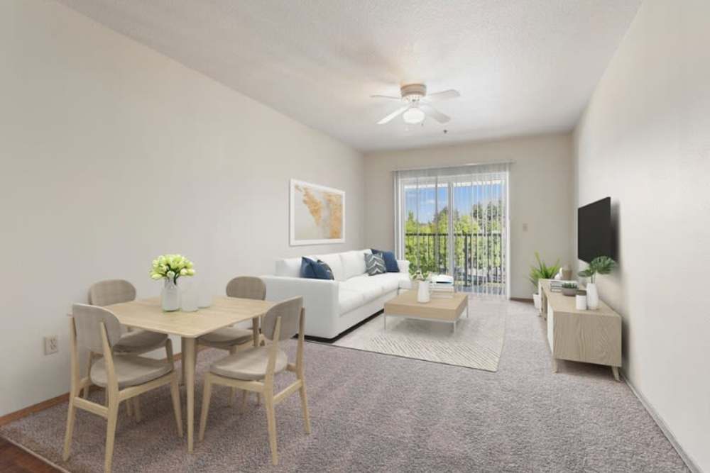 Dining table and living room with private balcony attached at Ventura Park Plaza Apartments in Portland, Oregon