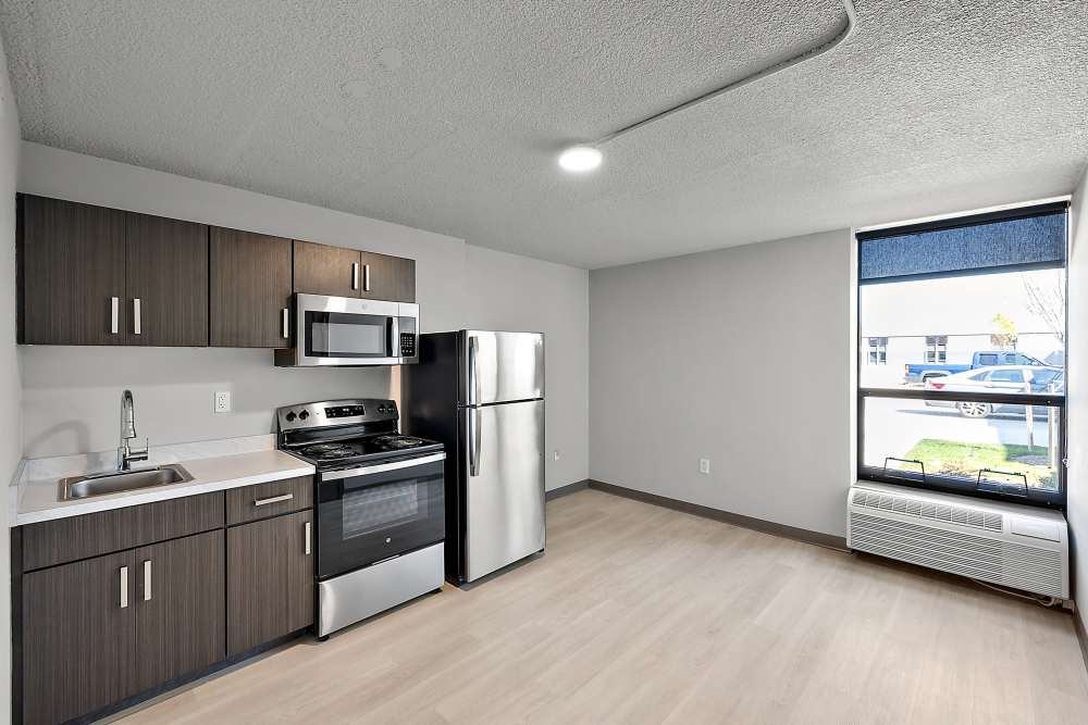 Kitchen and bar with appliances including refrigerator, microwave, oven, and cupboard storage at The Block at Sterling Heights in Sterling Heights, Michigan