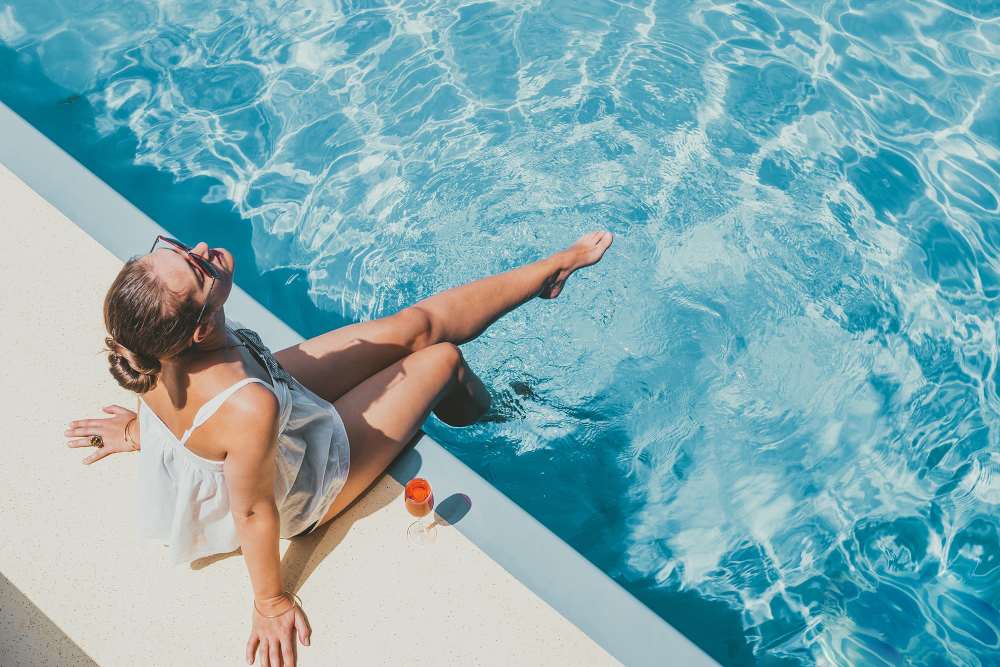 A woman sitting with her legs in the swimming pool at Arbors at Cahaba River in Birmingham, Alabama