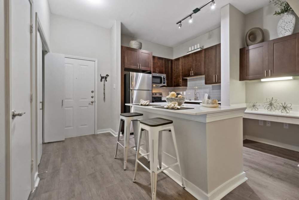 A kitchen with a bar and stools, providing a cozy and functional space for dining at Flatiron District at Austin Ranch, The Colony, Texas