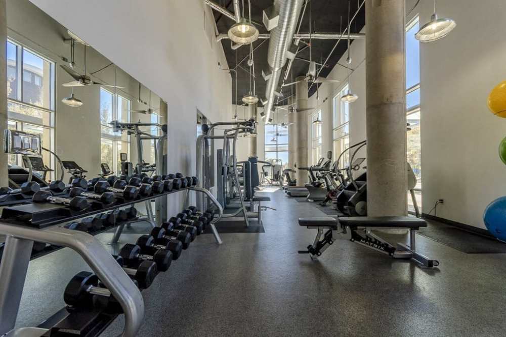 A gym room with exercise equipment and mirrors at Flatiron District at Austin Ranch, The Colony, Texas