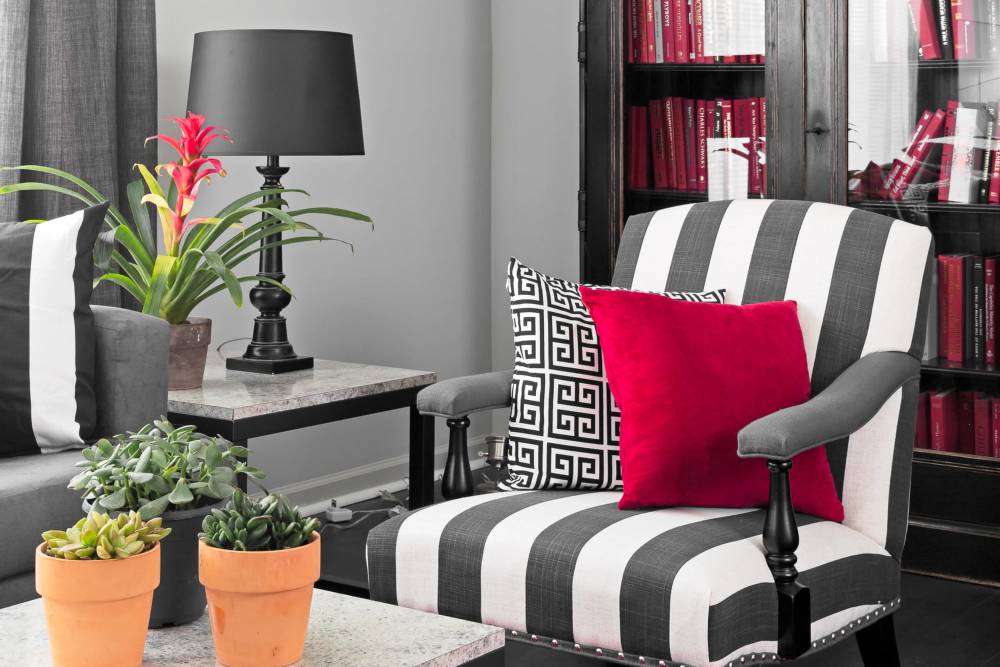 Modern apartment living room with potted plants and striped accent chair at The Gramercy in Manhattan, Kansas