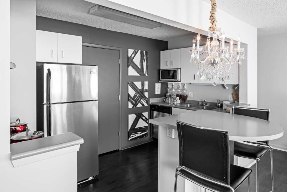 Luxury apartment kitchen with chandelier and stainless-steel appliances at The Gramercy in Manhattan, Kansas