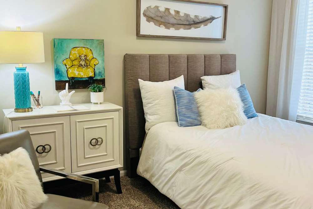A well-made bed, side table and arm chair in a model bedroom at Retreat at Johns Creek in Duluth, Georgia