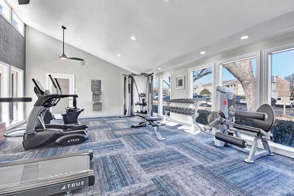 A gym room with exercise equipment and windows, perfect for a workout with a view at The Fairway Apartments in Plano, Texas