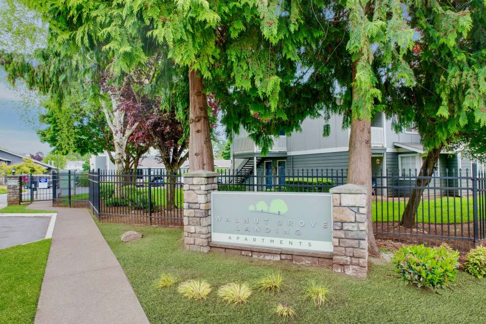 A walkway in front of the monument sign at Walnut Grove Landing Apartments in Vancouver, Washington