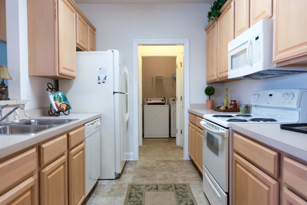 Tan cabinets and white appliances in an apartment kitchen at Cloisters at Carolina Forest in Myrtle Beach, South Carolina