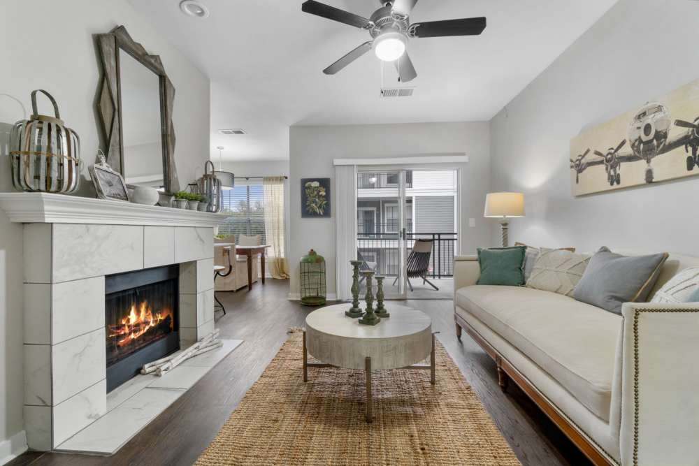 A warm living room featuring a fireplace and a plush couch at Flatiron District at Austin Ranch, The Colony, Texas