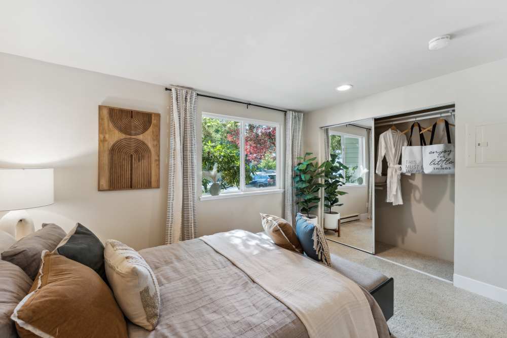 Spacious primary bedroom with plush carpeting, large windows, and plenty of closet space at Madison Sammamish Apartments in Sammamish, Washington