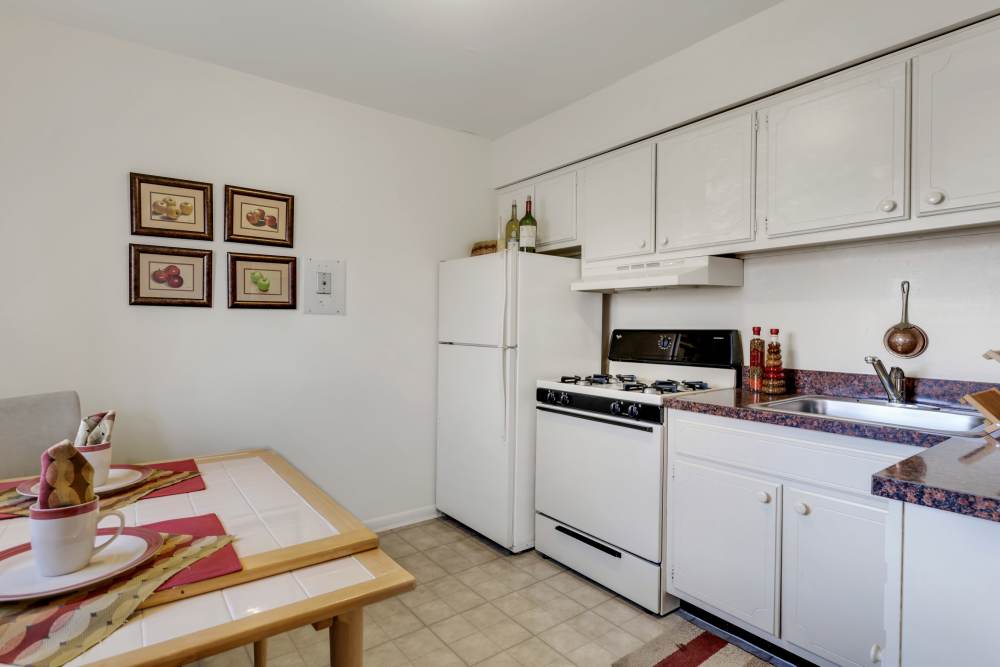 Open kitchen with dining table and white cabinets at Congress Apartment Homes in Allentown, Pennsylvania