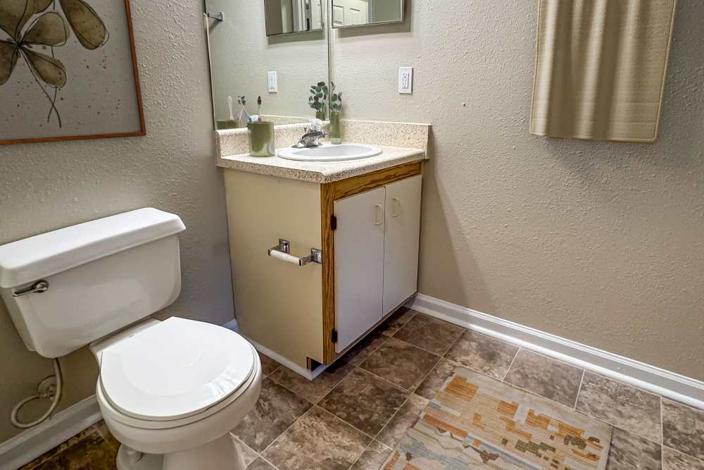 Well-lit tiled bathroom at at Greenleaf Apartments in Phenix City, Alabama