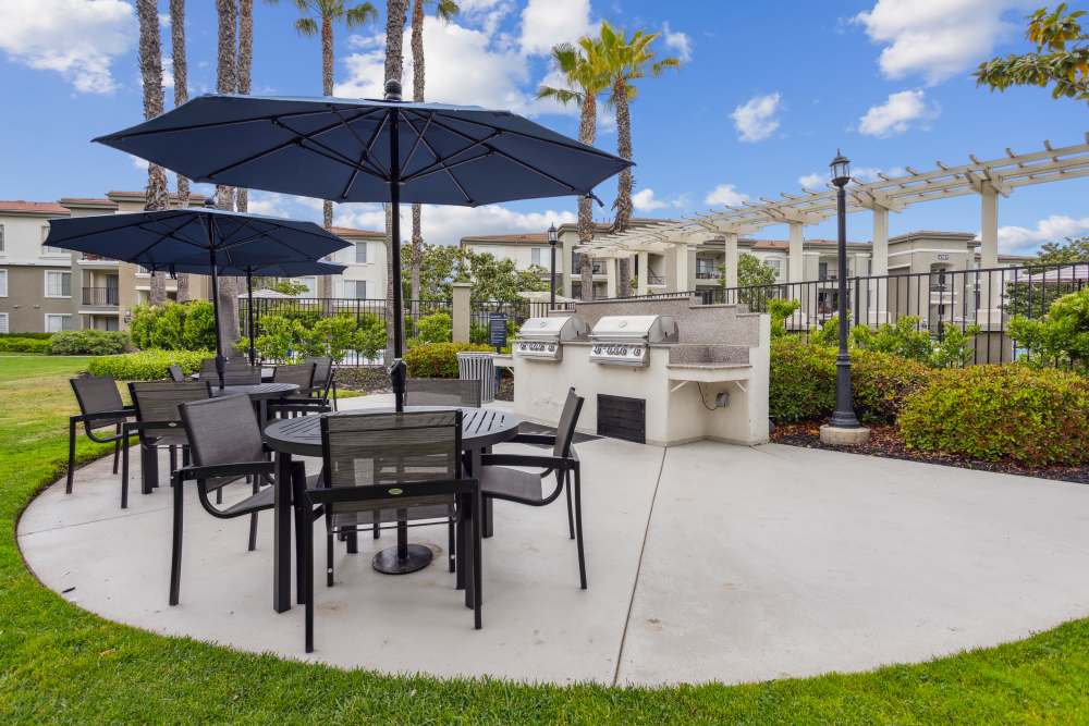 Outdoor resident BBQ area with tables and umbrellas at Avery at Moorpark in Moorpark, California