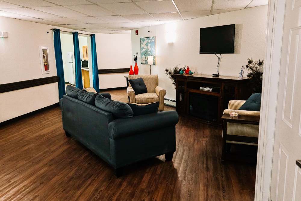 Resident seating area with large chairs and flat-screen TV at Bramblewood in New Haven, Michigan