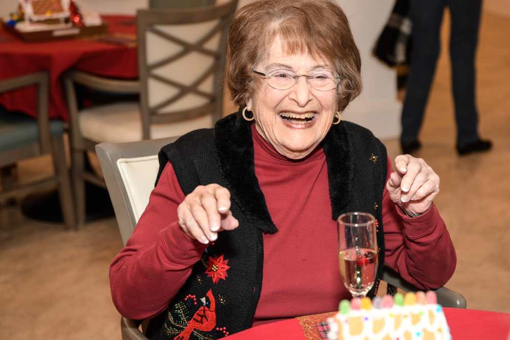 Gleeful resident with a glass of wine and a gingerbread house at Haywood Estates in Greenville, South Carolina