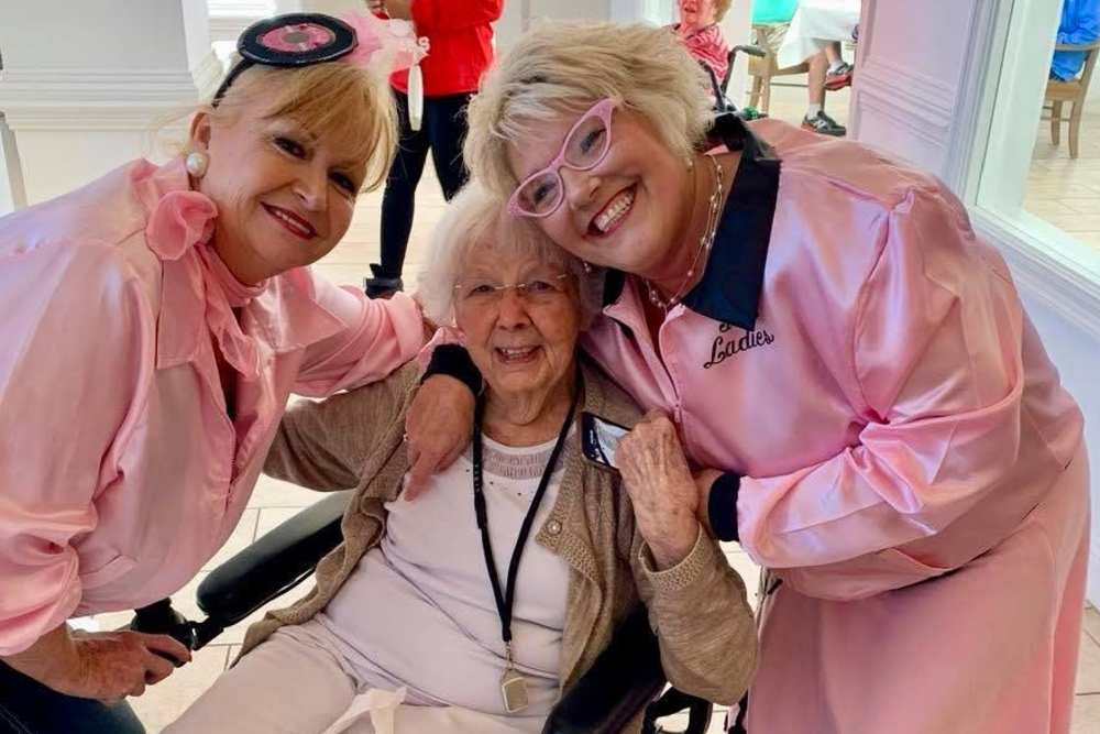 Two staff members dressed in bright pink with a resident at Deepwood Estates in Lexington, South Carolina