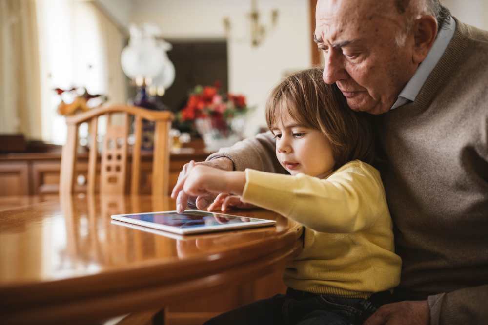 Resident with grandchild playing with an iPad at Watermere Highlands in Arlington, Texas